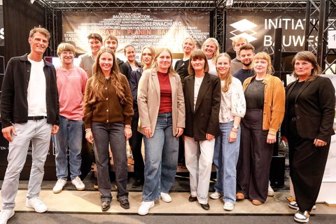 Große Gruppe von Teilnehmenden und Preisträger:innen auf einer Bühne bei einer Veranstaltung.