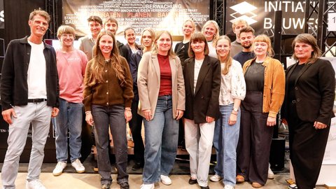 Große Gruppe von Teilnehmenden und Preisträger:innen auf einer Bühne bei einer Veranstaltung.