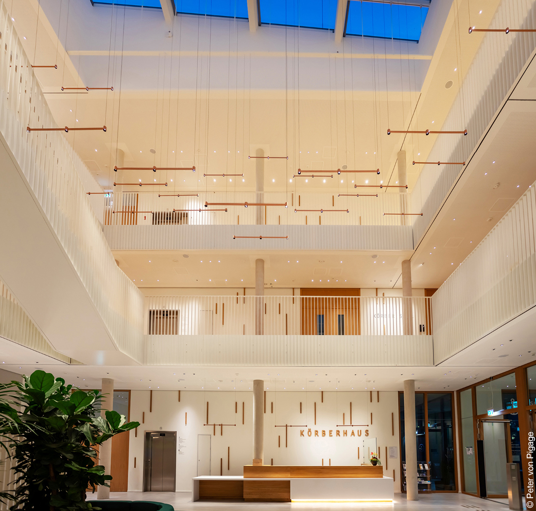 Eingangsbereich eines Gebäudes mit Galerien und einem überdimensionalen Mobilé, das von der Decke hängt.