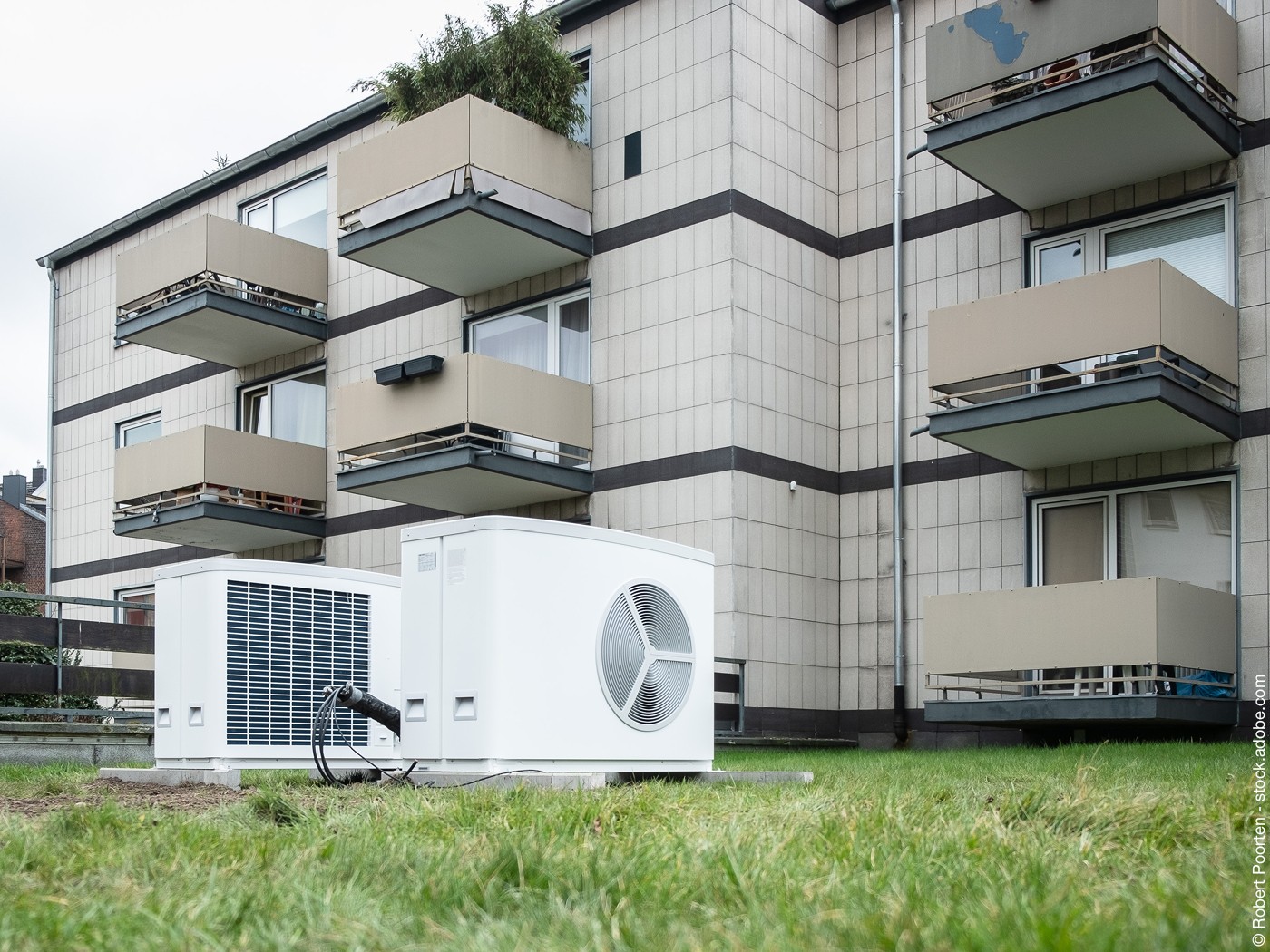 Wärmepumpe vor einem Mehrfamilienhaus