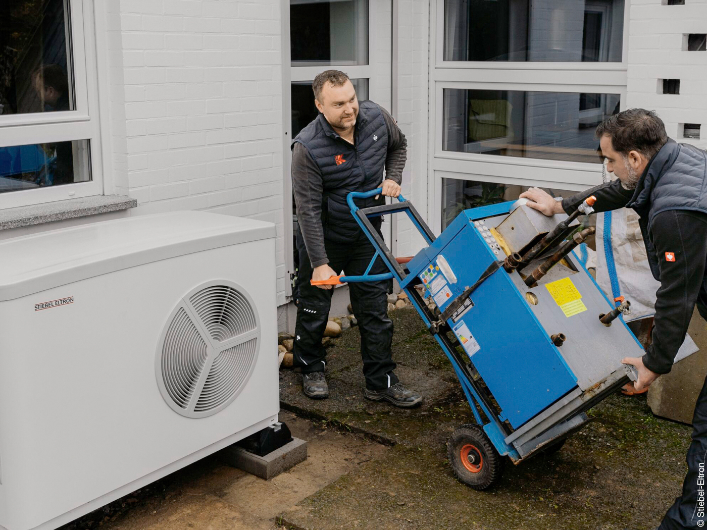 Handwerker tauschen ein altes Heizgerät gegen eine neue Wärmepumpe
