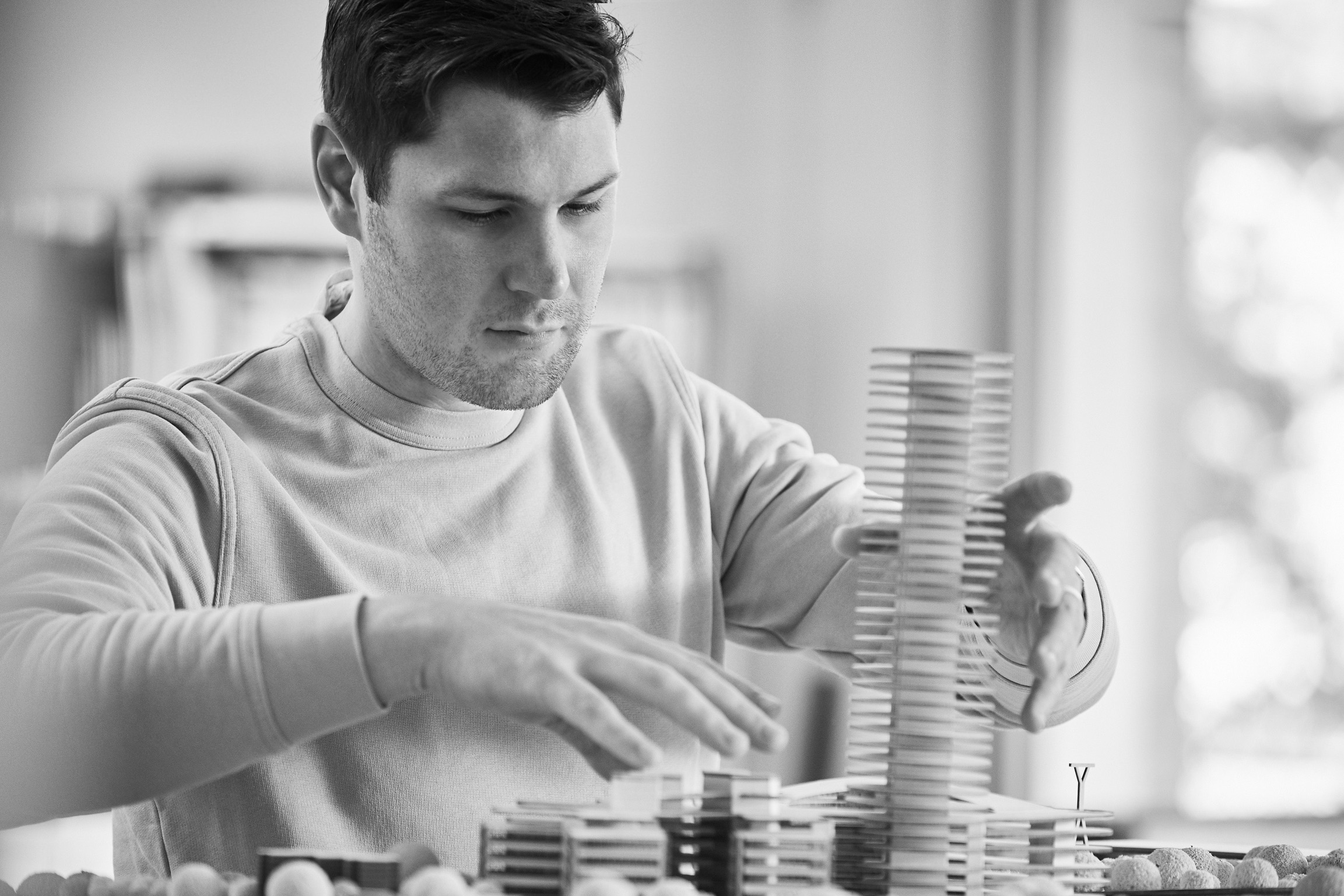 DAB-Kolumnist Fabian P. Dahinten sitzt vor einem Architekturmodell