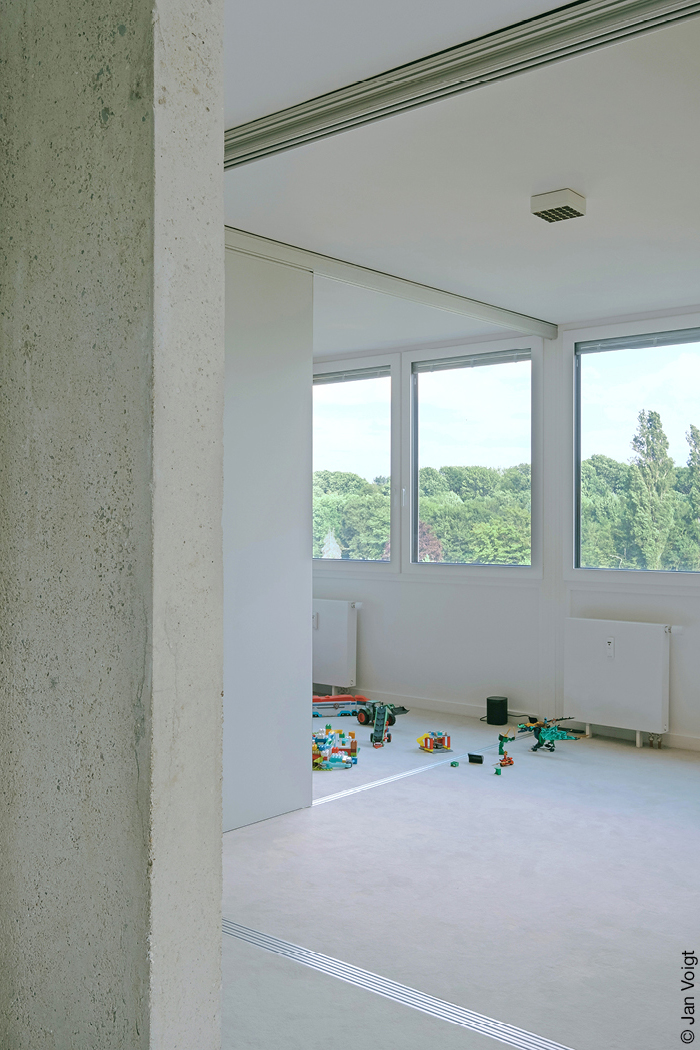 Kinderzimmer mit halboffener Schiebewand als Raumtrenner, auf dem Boden liegt Spielzeug.