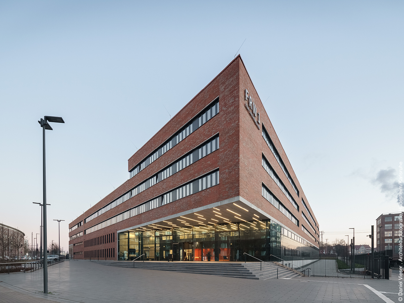 Rechteckiger Bau mit roten Ziegelsteinen und breiten Fensterfronten.