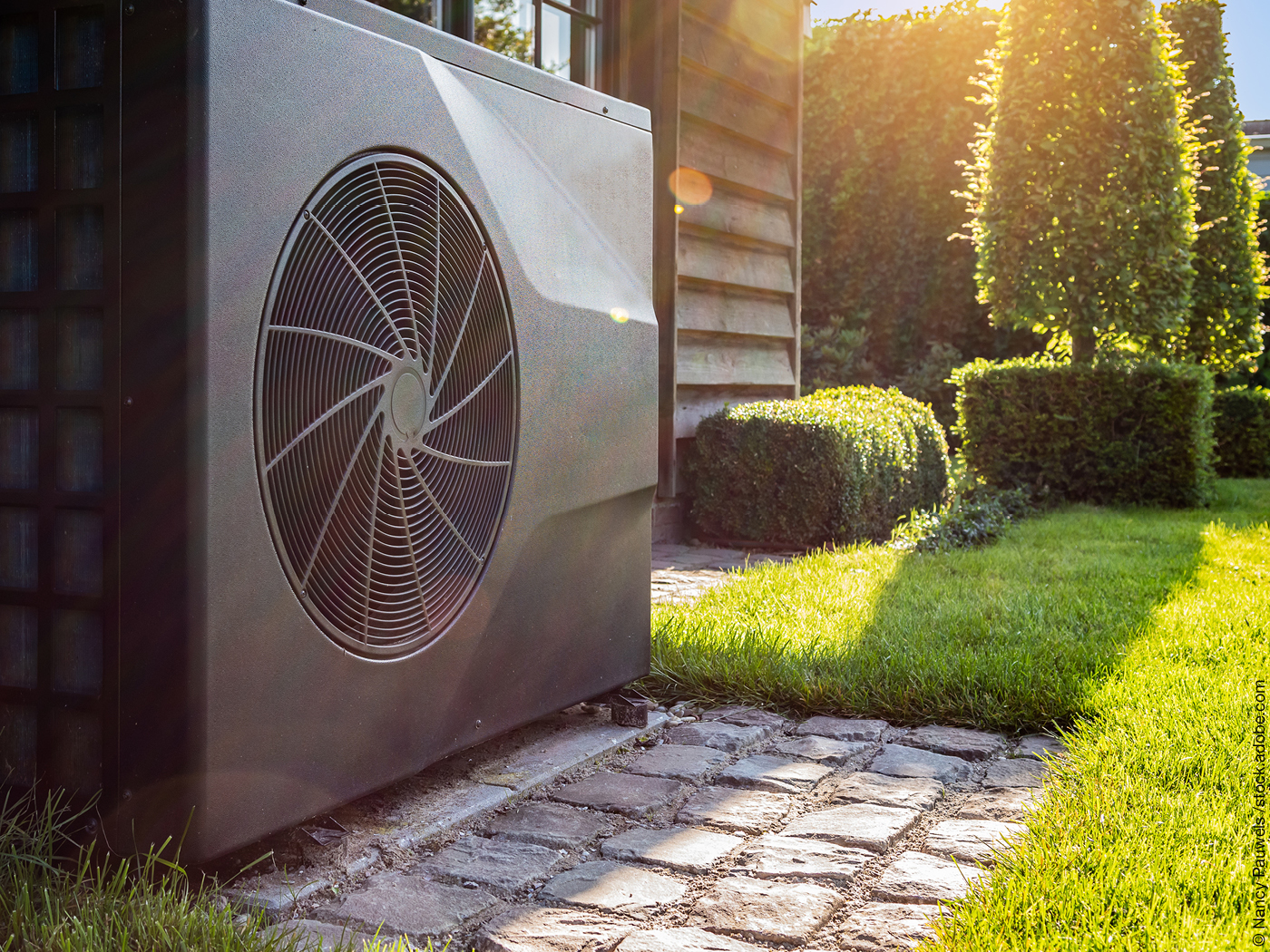 Wärmepumpe im Garten vor Holzhaus