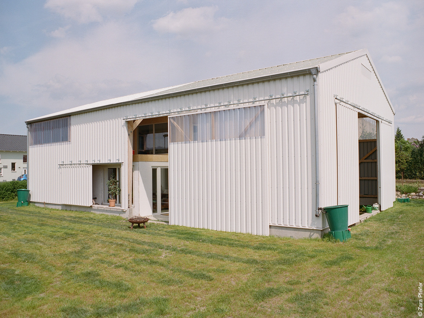 Weiße Industriehalle mit Schiebetüren und Wohnhaus darin