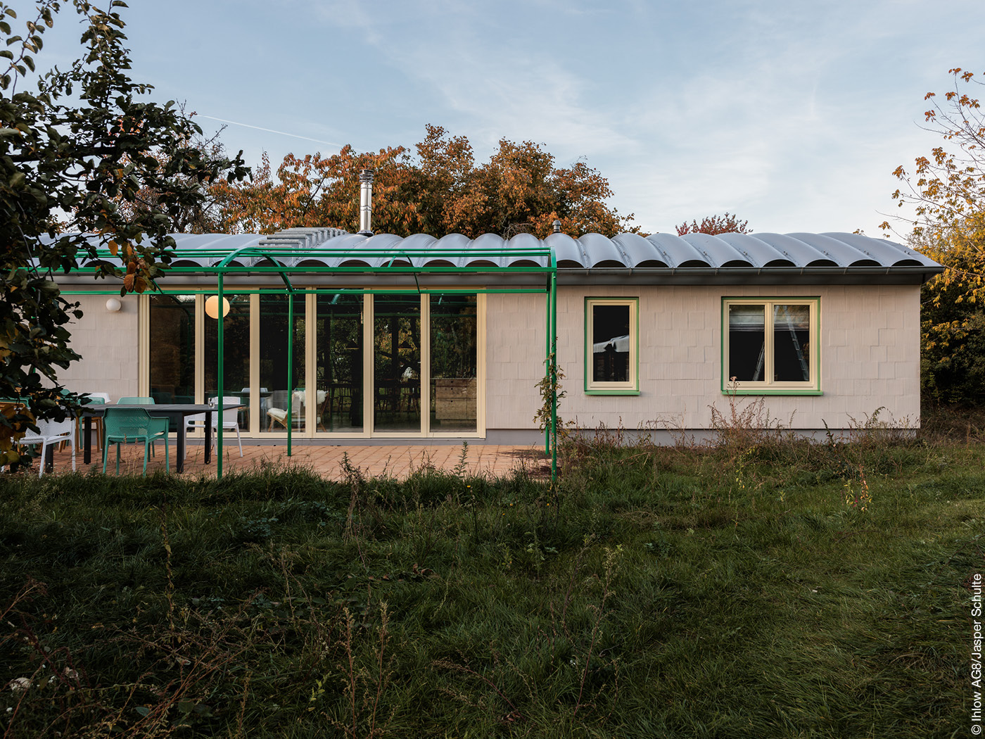 Wohnhaus mit Tonnendach, grüner Pergola und Terrasse