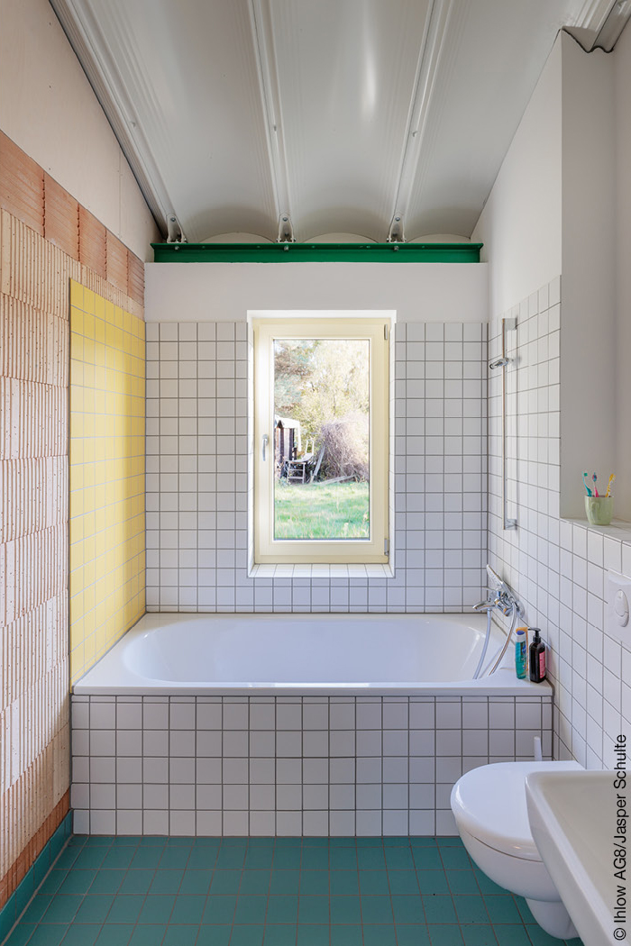 Gefliestes Badezimmer mit Badewanne und sichtbarem Mauerwerk