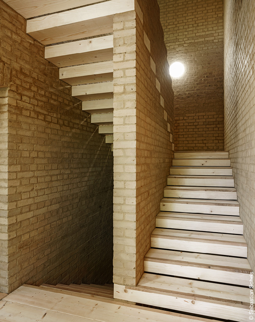 Treppenhaus mit Holztreppen und Lehmsteinen