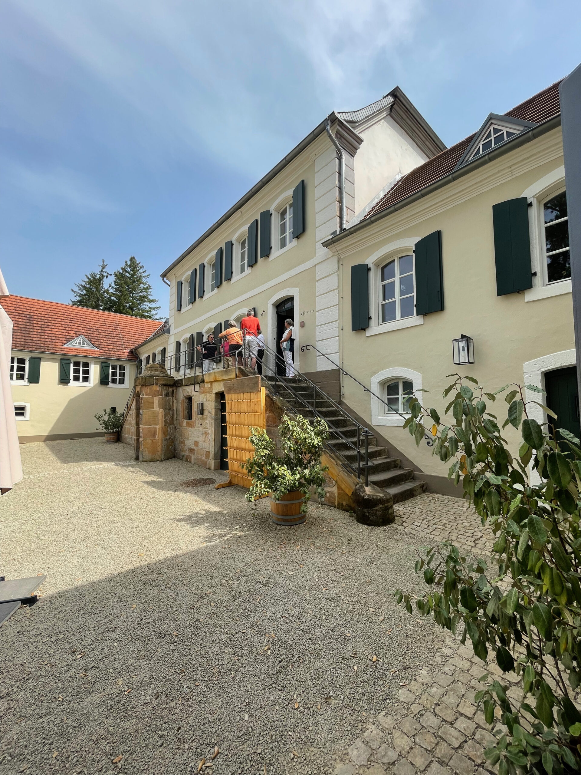 Innenhof eines beigegestrichenen Jagdschlosses mit Treppenaufgang.