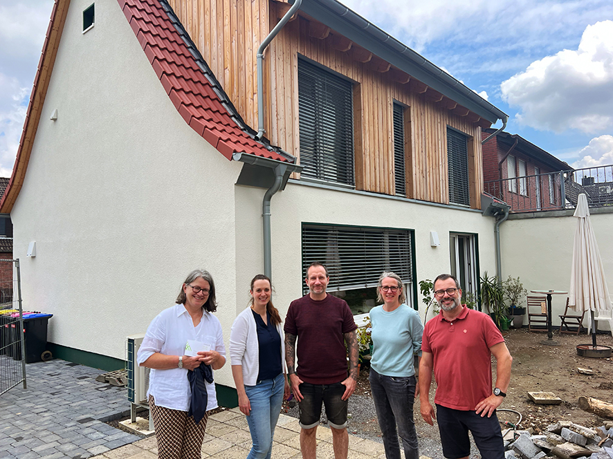 Frauen und Männer vor einem sanierten Siedlungshaus in Gelsenkirchen.