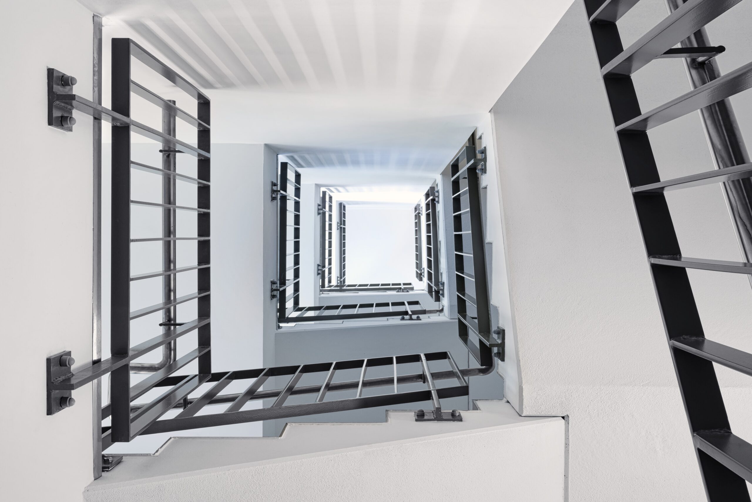 Treppenhaus mit schwarzen Geländern und weißen Wänden