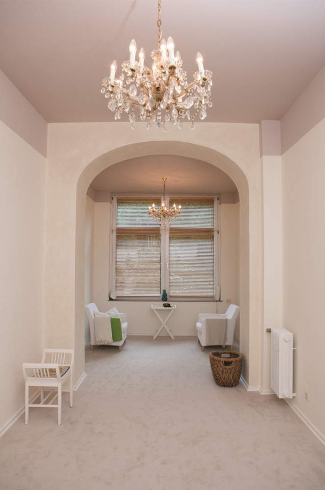 Raum in erdigen Farbtönen mit Kronleuchter und Rundbogen