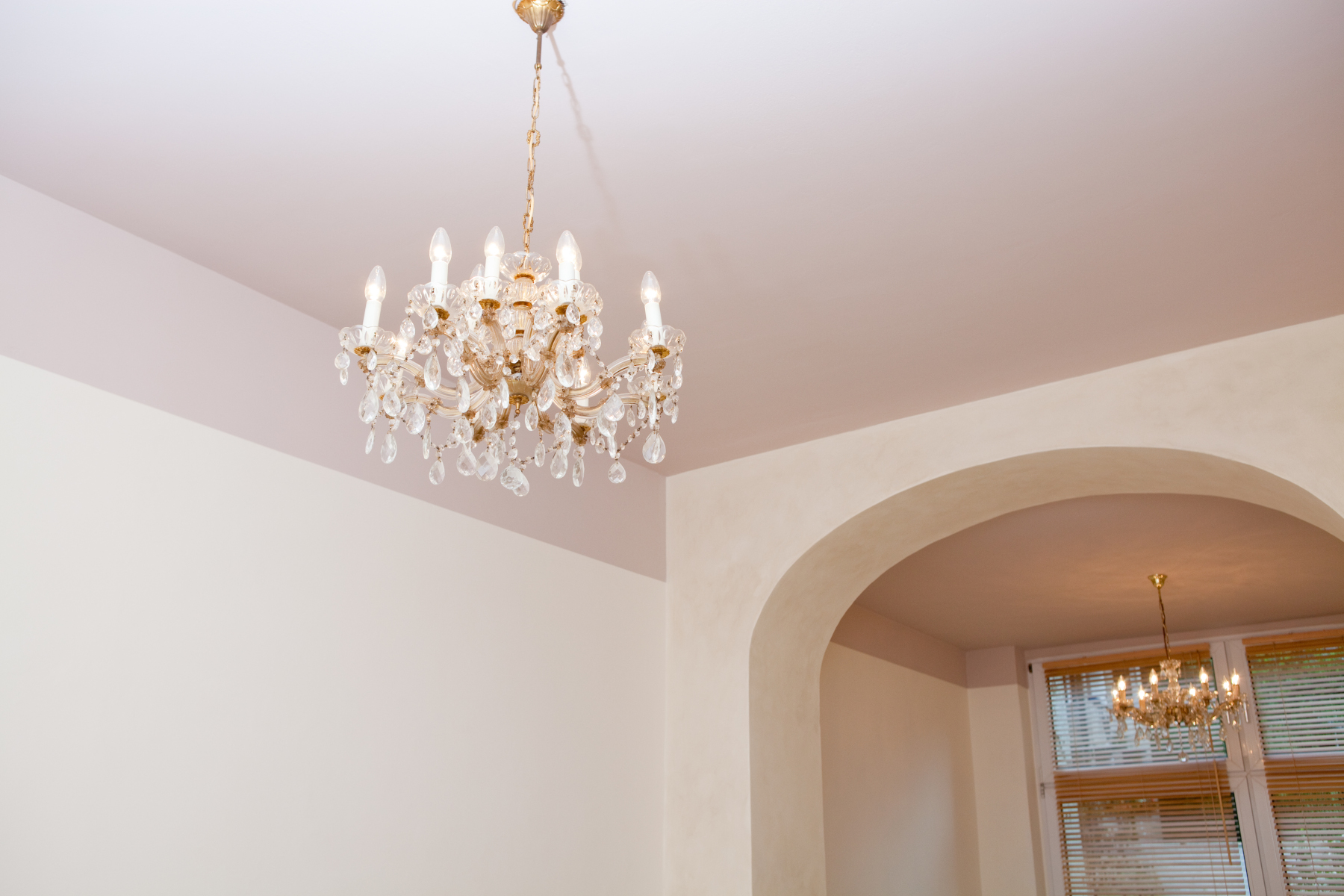 Farblich abgesetzte Decke in erdigem Farbton mit Kronleuchter und Rundbogen