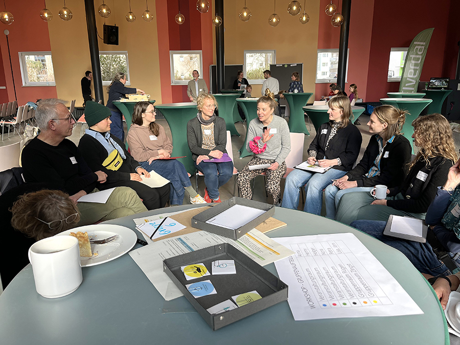 Neun Menschen unterhalten sich sitzend im Halbkreis 