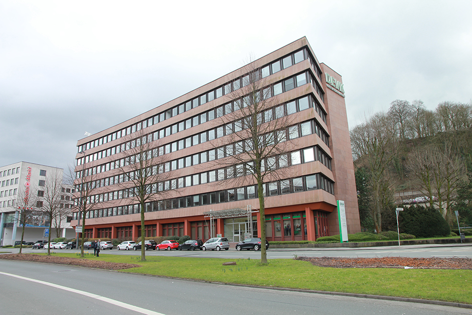 An der Fassade des Bürogebäudes domoiniert die Farbe grau, die Struktur ist flach und streng horizontal.