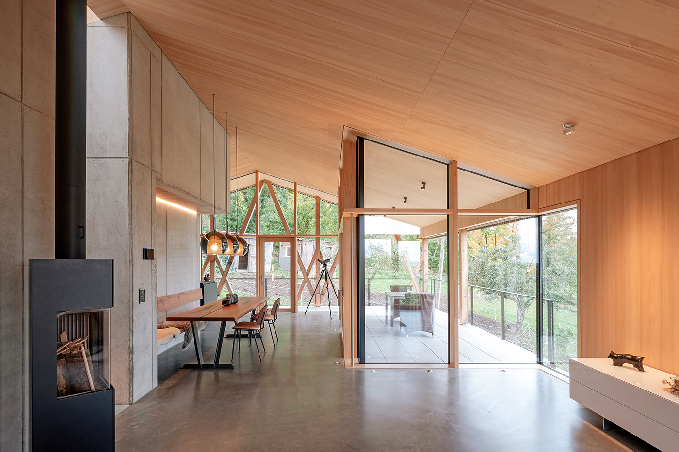Wohnraum mit Glasflächen, Holzdecke und Sichtbetonwand