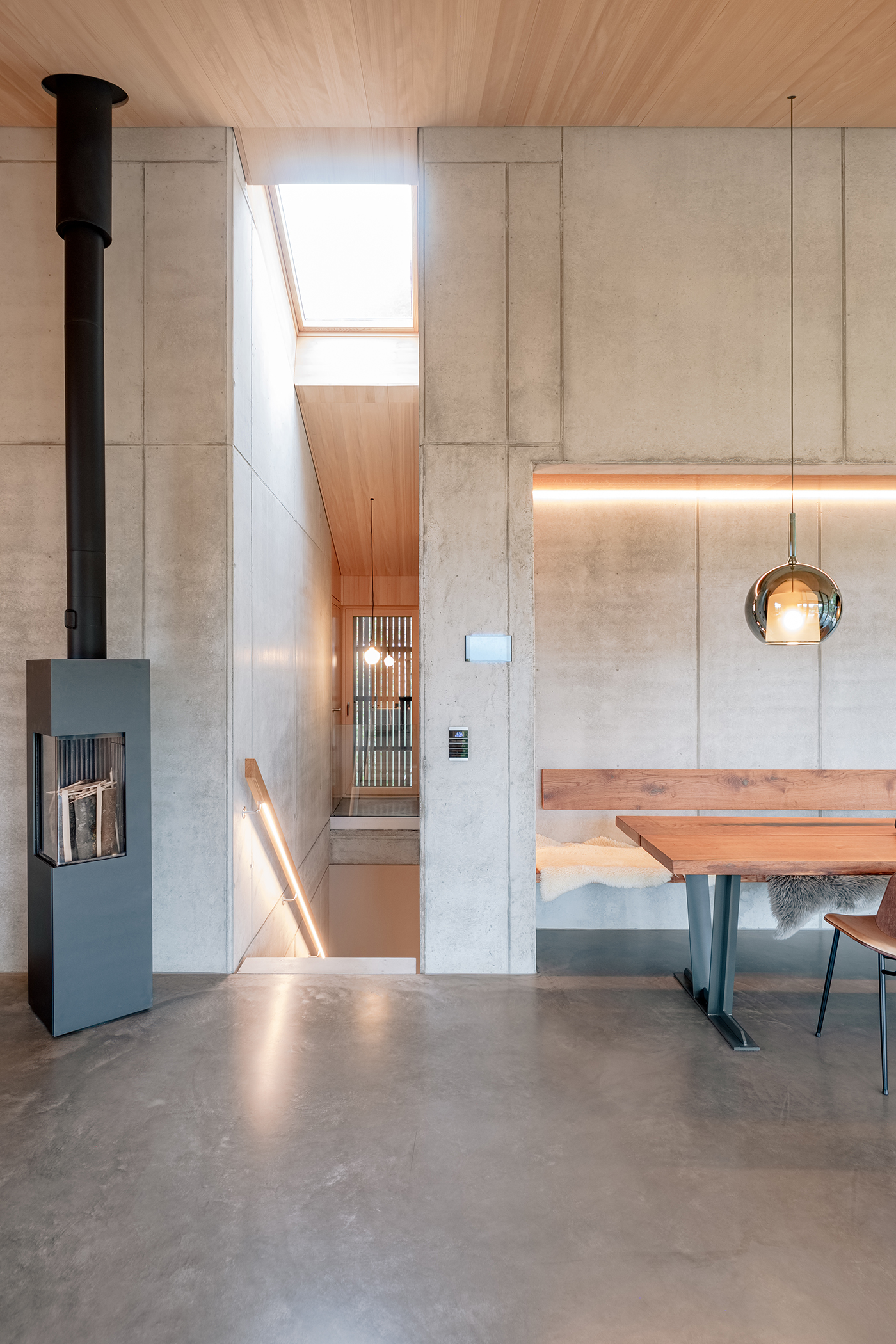 Treppe zwischen Sichtbetonwänden und Kamin