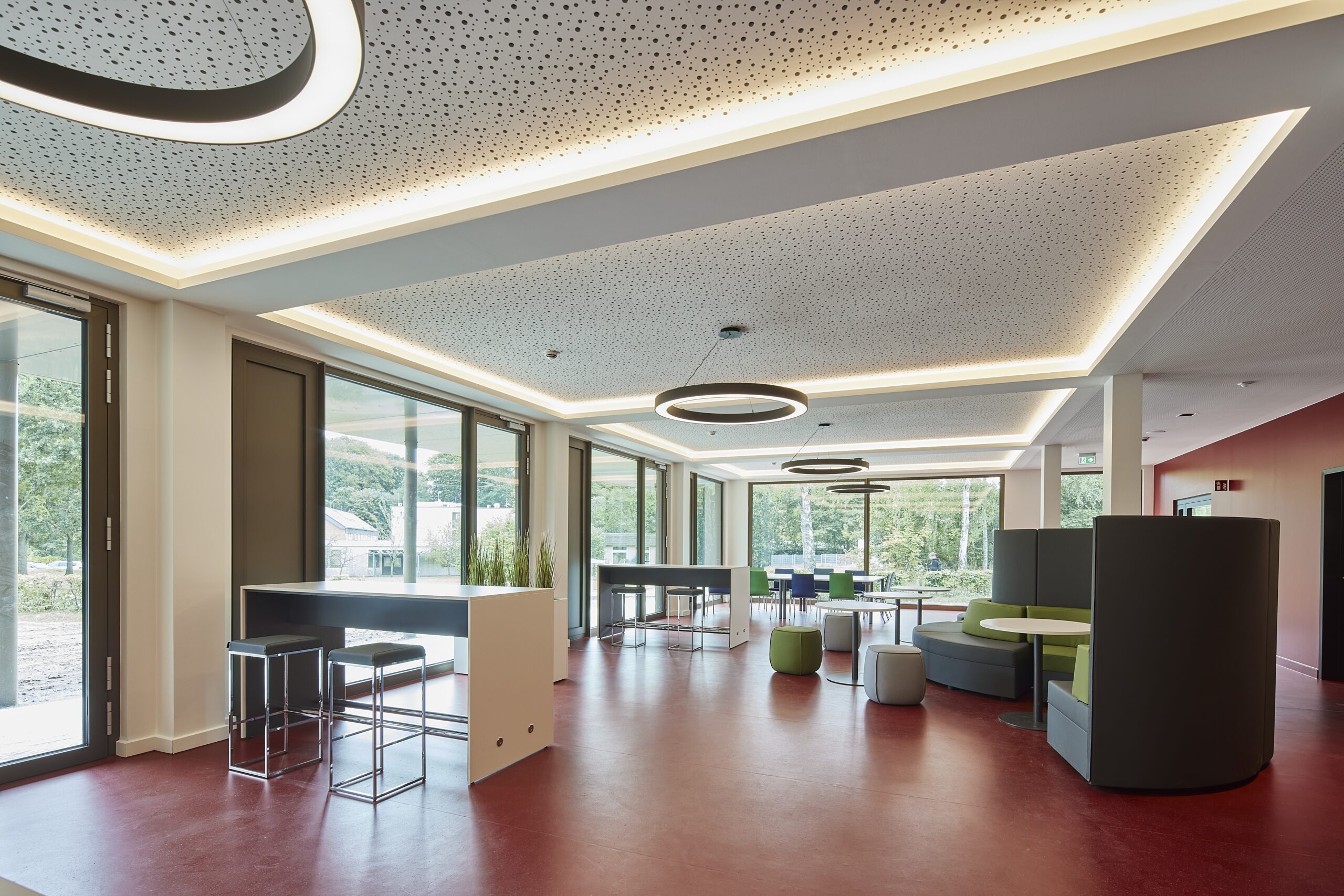 Schulfoyer mit Tischen, Stühlen, Sitzbänden und Sitzhockern.