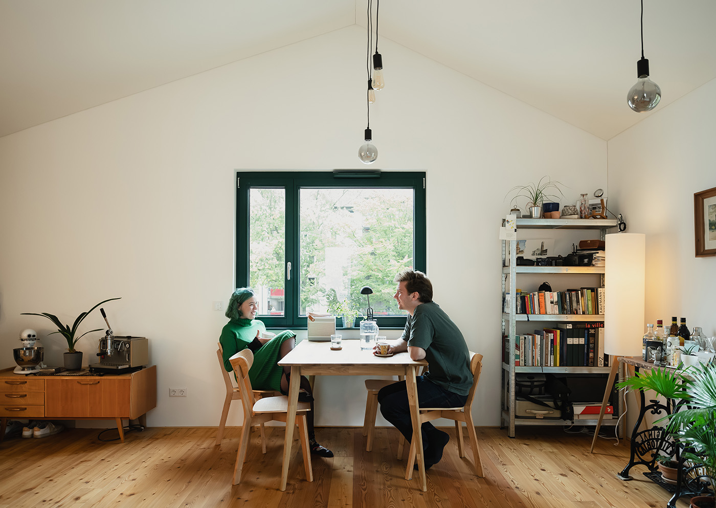 Wohnraum mit einem Tisch, an dem ein Pärchen sitzt