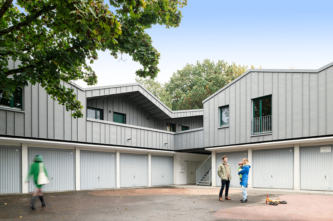 Wohnungen auf Garagen mit grauer Fassade zúdn gezacktem Dach