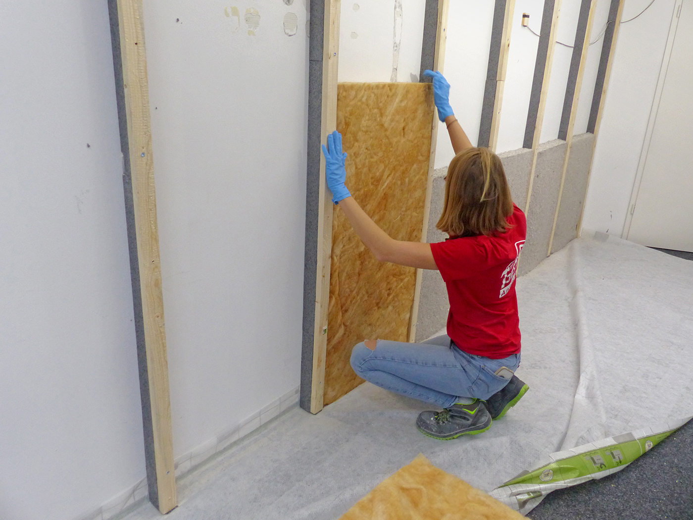 Frau dämmt eine Wand von innen