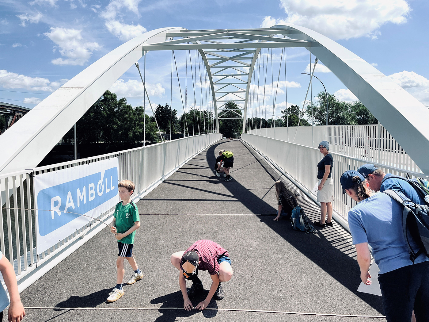 Kinder mit Zollstöcken auf einer Fußgängerbrücke