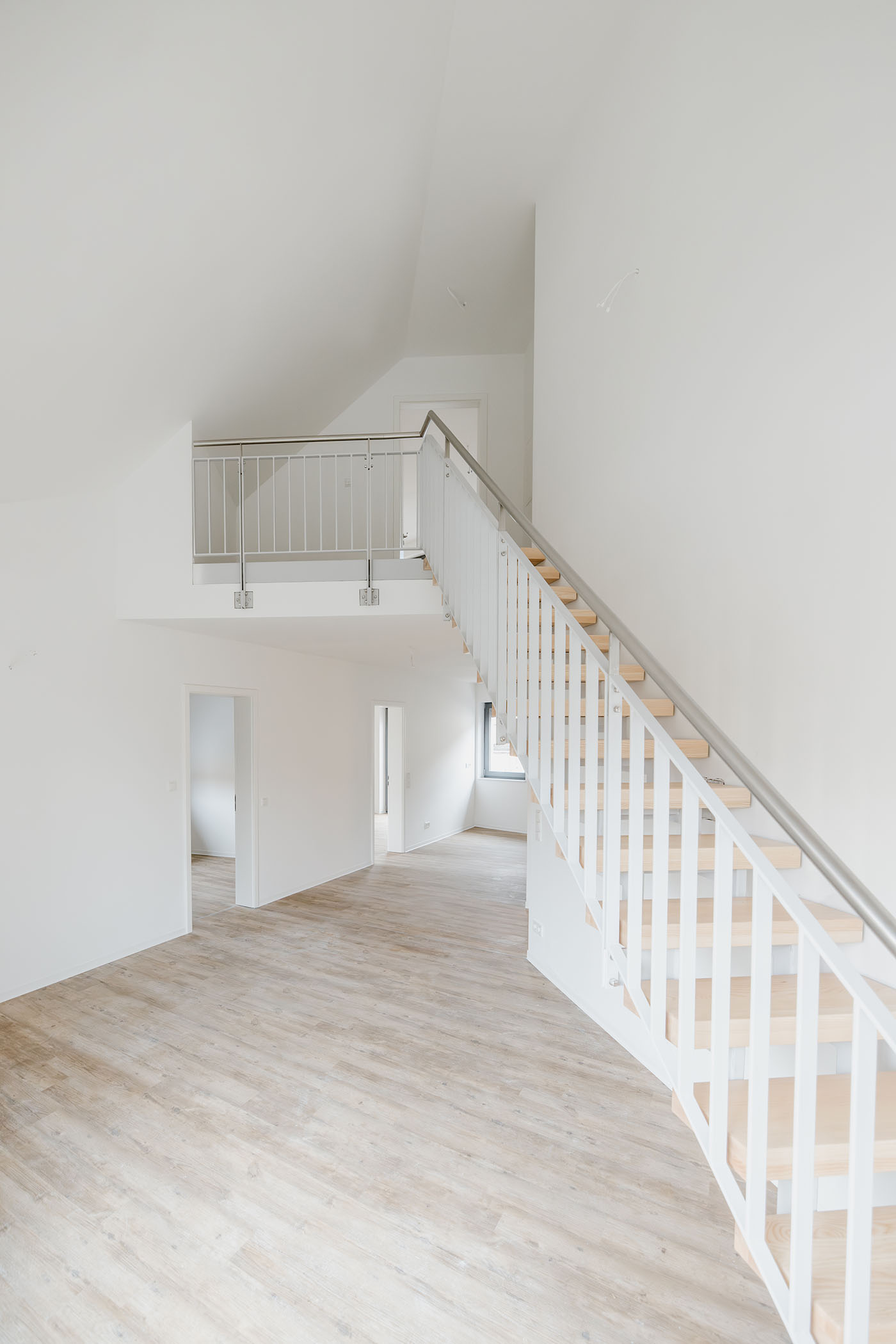 Maisonettewohnung mit einem weiß melierten Boden und einer weißen Treppe.