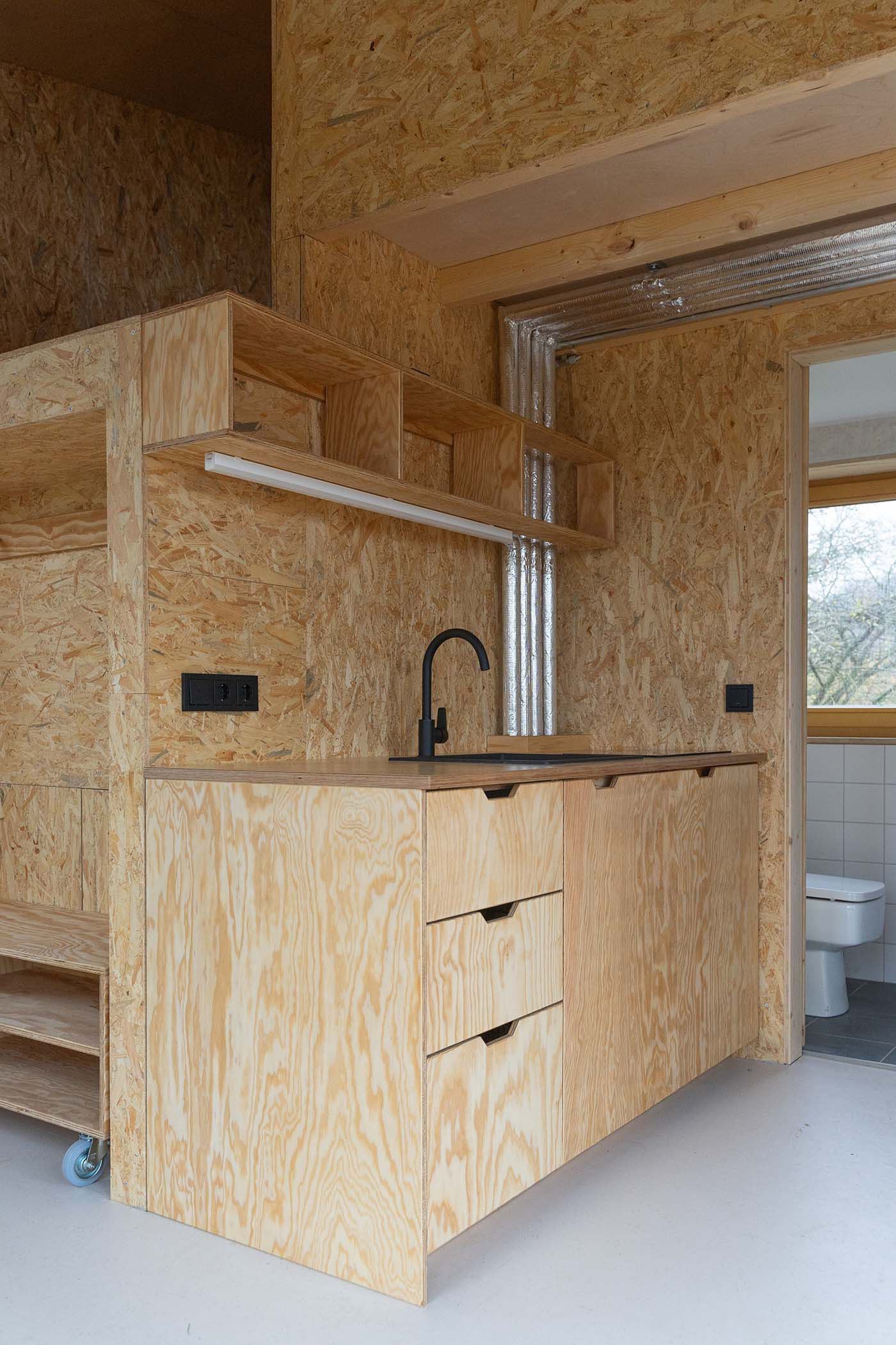 Küche mit Spanplattenwand und Front aus Funierholz.