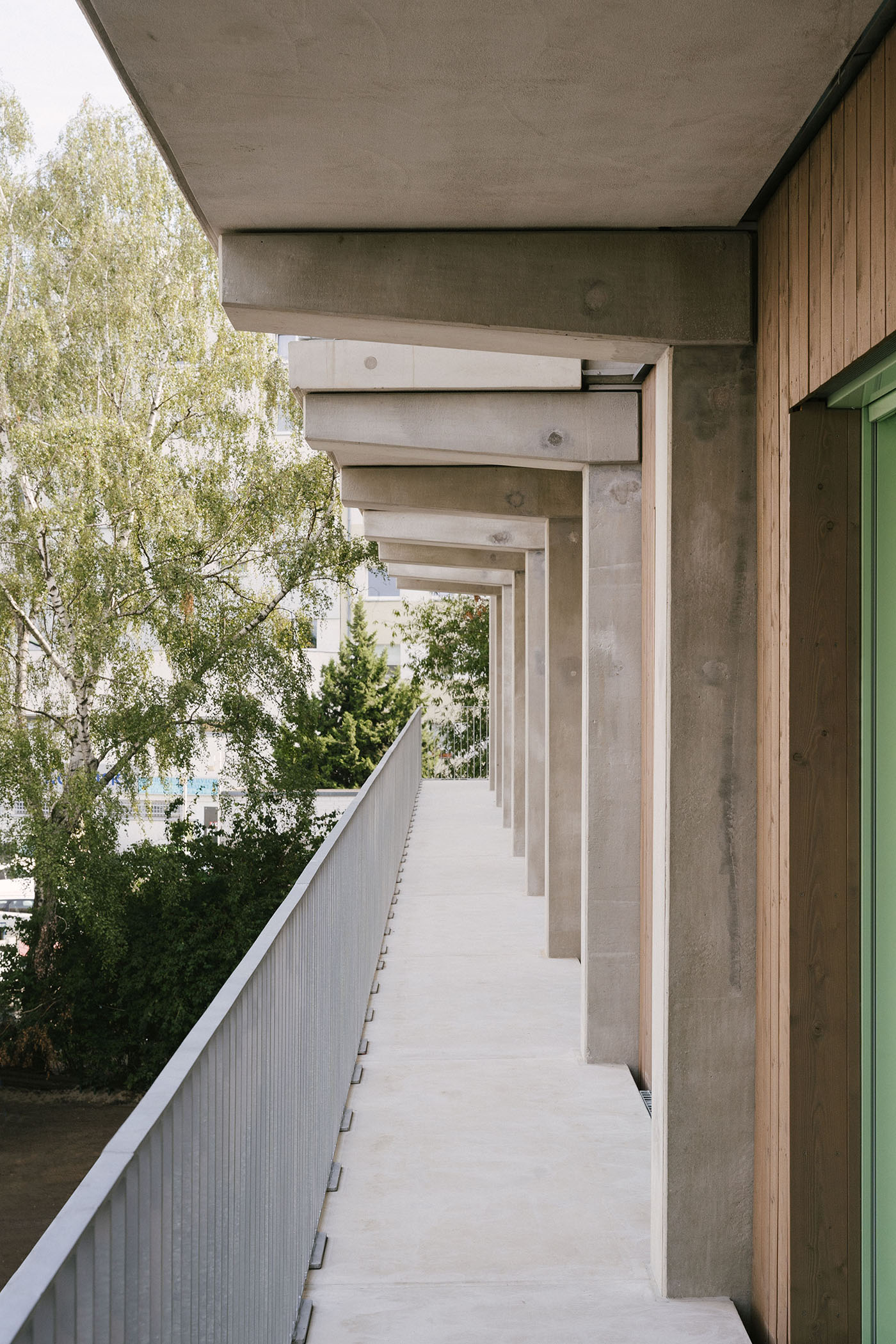 Langgezogener Balkon an einem Haus mit Trägern aus Beton an den Wänden und einer Holzfassade