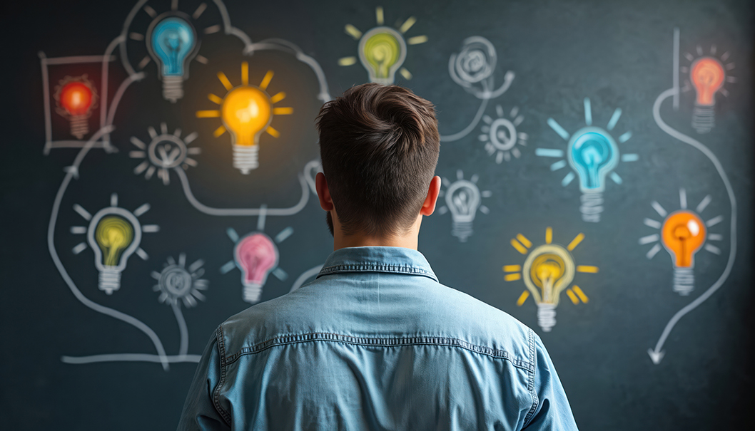 Ein Mann steht vor eine Tafel, auf der viele leuchtende Glühbirnen abgebildet sind
